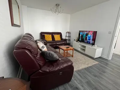 a living room with a brown leather couch and a tv at Tranquil Haven: 3-BR House in Great Burstead