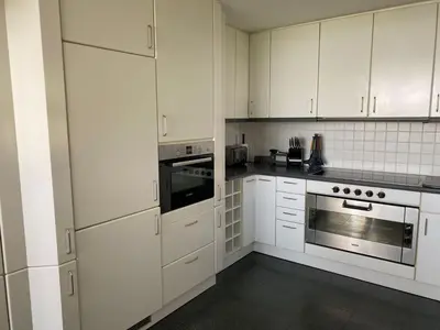a white kitchen with white cabinets and an oven at La de da Frinton on Sea in Frinton-on-Sea