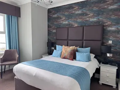 a bedroom with a large bed with a painting on the wall at Camelia Hotel in Southend-on-Sea
