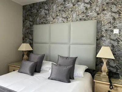 a bedroom with a bed with two lamps and a wall at Camelia Hotel in Southend-on-Sea