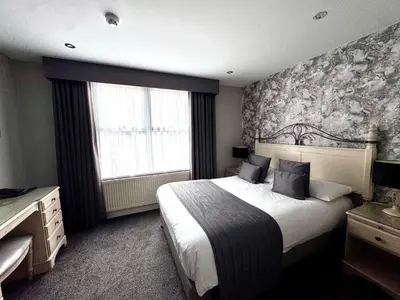 a bedroom with a large bed and a window at Camelia Hotel in Southend-on-Sea