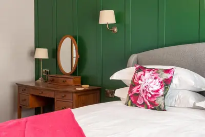 a bedroom with green walls and a bed with a mirror at The Crown Pub and Hotel in Manningtree