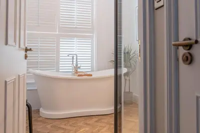 a white bath tub in a bathroom with a window at The Crown Pub and Hotel in Manningtree