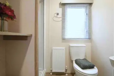 a bathroom with a toilet and a window and a radiator at Rohannah Luxe Coastal Escape, Cooper Beach East Mersea in East Mersea