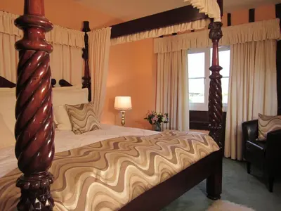 a bedroom with a canopy bed and a window at Colston Hall Farmhouse B&B in Framlingham