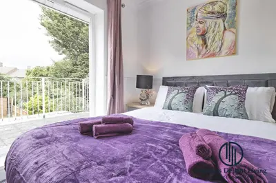 a bedroom with a purple bed with a large window at Purple Velvet - 2 Bed Home Spacious - Basildon Essex Upto 5 Guests, Free Wifi , Free Parking in Basildon