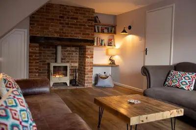 a living room with a couch and a fireplace at Baytree Cottage Framlingham in Framlingham