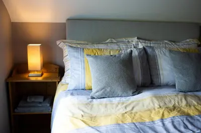 a bed with blue and white pillows and a lamp at Baytree Cottage Framlingham in Framlingham