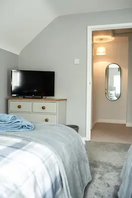 a bedroom with a bed and a tv on a dresser at Baytree Cottage Framlingham in Framlingham