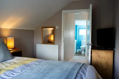 a bedroom with a bed and a television and a bathroom at Baytree Cottage Framlingham in Framlingham