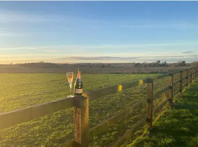 a bottle of wine and two glasses on a fence at Near Woodbridge The Annexe Eyke Fantastic views with Dog secure Garden and Paddock in Eyke