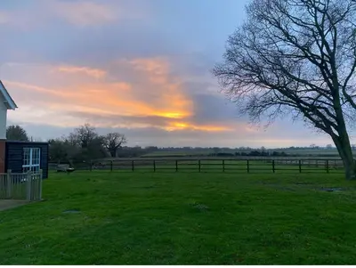 a sunset in a field with a fence and a tree at Near Woodbridge The Annexe Eyke Fantastic views with Dog secure Garden and Paddock in Eyke