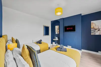 a room with two beds and blue walls at Pristine House - Sleeps 10 - Amazing Location in Ipswich