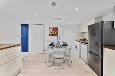 a white kitchen with a table and a refrigerator at Pristine House - Sleeps 10 - Amazing Location in Ipswich