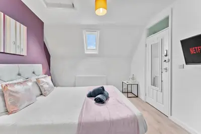 a bedroom with a white bed with a purple wall at Pristine House - Sleeps 10 - Amazing Location in Ipswich