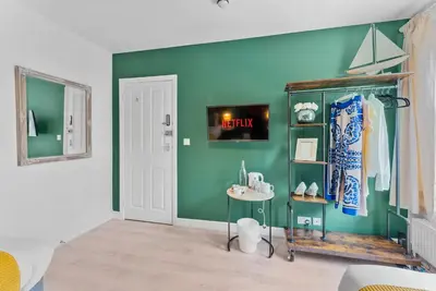 a room with a green wall and a shelf with shoes at Pristine House - Sleeps 10 - Amazing Location in Ipswich
