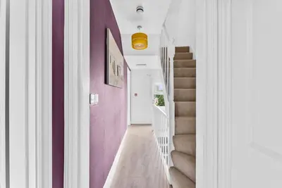 a hallway with purple and white walls and stairs at Pristine House - Sleeps 10 - Amazing Location in Ipswich