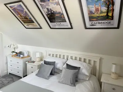 a bedroom with a white bed with four pictures on the wall at The Top Floor in Stretham