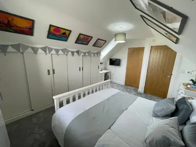 a bedroom with a large white bed and a couch at The Top Floor in Stretham
