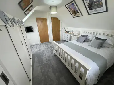 a bedroom with a large white bed and a dresser at The Top Floor in Stretham