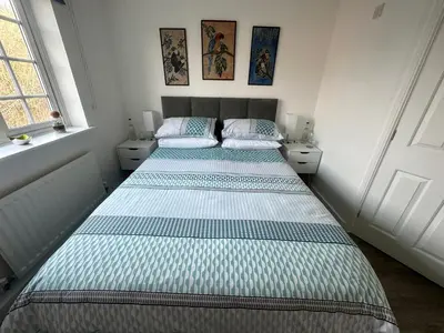 two beds in a small bedroom with two windows at Chez Ana in Saxmundham