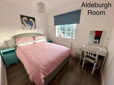 a bedroom with a bed with a pink bedspread and a window at Chez Ana in Saxmundham
