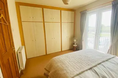 a bedroom with a bed and a large window at River Lark Lodge in Ely