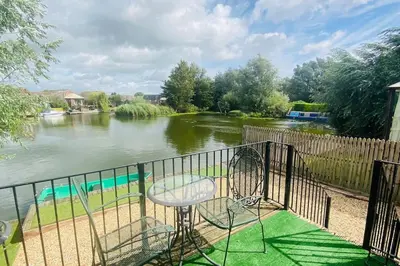 a balcony with a chair and a river at River Lark Lodge in Ely