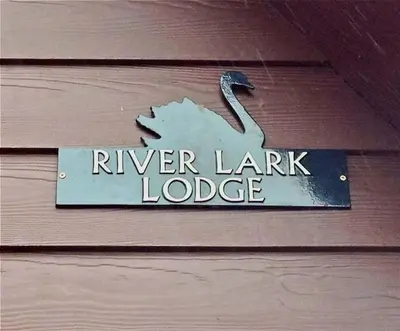 a sign that says river lender lodge on a wooden wall at River Lark Lodge in Ely