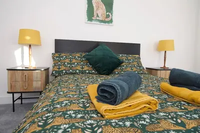 a bed with blankets and pillows on top of it at Beautiful large 3-bed coastal flat with parking. in Frinton-on-Sea