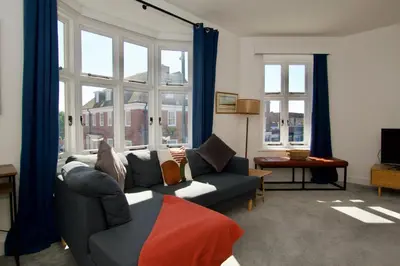 a living room with a couch and windows at Beautiful large 3-bed coastal flat with parking. in Frinton-on-Sea