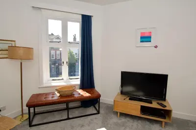 a living room with a flat screen tv and a table at Beautiful large 3-bed coastal flat with parking. in Frinton-on-Sea