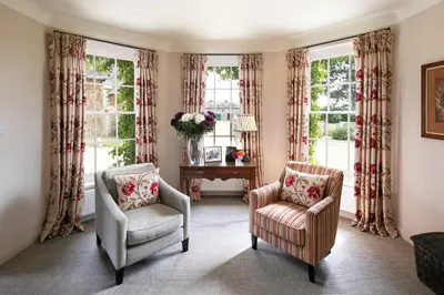a living room with two chairs and windows at Butley Priory Farmhouse 12 in Woodbridge