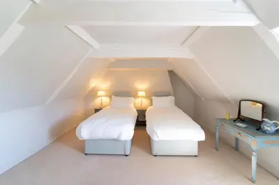 a attic bedroom with two beds and a table at Butley Priory Farmhouse 12 in Woodbridge