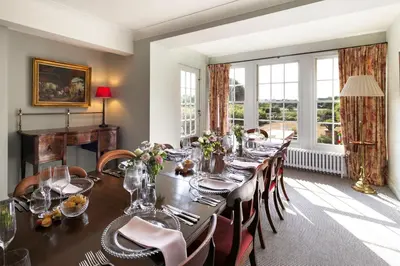 a dining room with a long table and chairs at Butley Priory Farmhouse 12 in Woodbridge