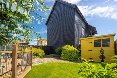 a house with a black roof and a yellow garage at Escape in Aldeburgh