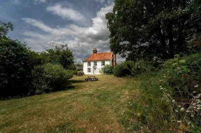 a white house with a bench in front of it at 5 Bed Farmhouse Suitable for Contractors Private Parking in Potter Street