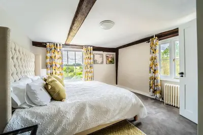 a bedroom with a large bed with yellow curtains at 5 Bed Farmhouse Suitable for Contractors Private Parking in Potter Street