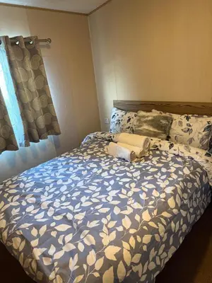 a bedroom with a bed with a blue and white comforter at Seawick Caravan 922 in Clacton-on-Sea