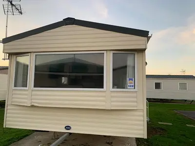 a tiny house with a large window in a yard at Seawick Caravan 922 in Clacton-on-Sea