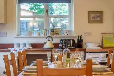 a kitchen with a table with plates and wine glasses at Stable Cottage in Semer