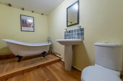 a bathroom with a tub and a sink and a toilet at Stable Cottage in Semer