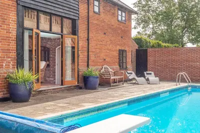 a house with a swimming pool next to a brick wall at Stable Cottage in Semer