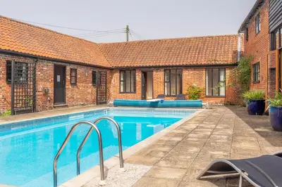 a swimming pool in front of a brick building at Stable Cottage in Semer