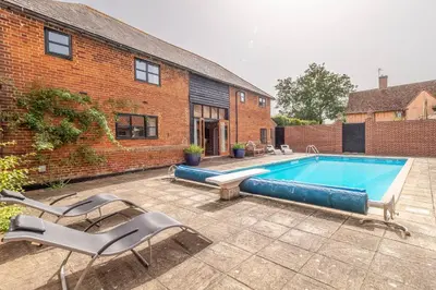 a swimming pool in front of a brick building at The Old Barn in Semer