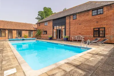 a swimming pool in front of a brick building at The Old Barn in Semer