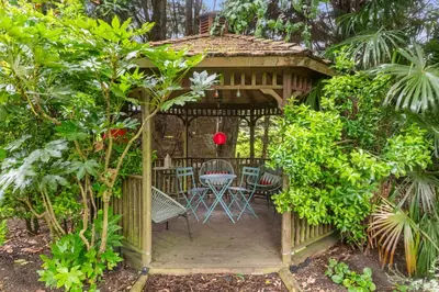 a wooden gazebo with a table and chairs in a garden at Attractive 2 storey, 2 bedroom barn in Long Melford in Long Melford
