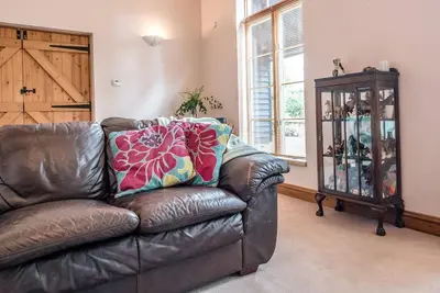 a leather couch in a living room with a cabinet at The Old Coach House, Leiston in Leiston