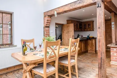 a wooden table with chairs and a bottle of wine at The Old Coach House, Leiston in Leiston