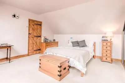 a bedroom with a large bed and a wooden door at The Old Coach House, Leiston in Leiston